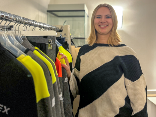 Young woman standing next to line of protective clothing.